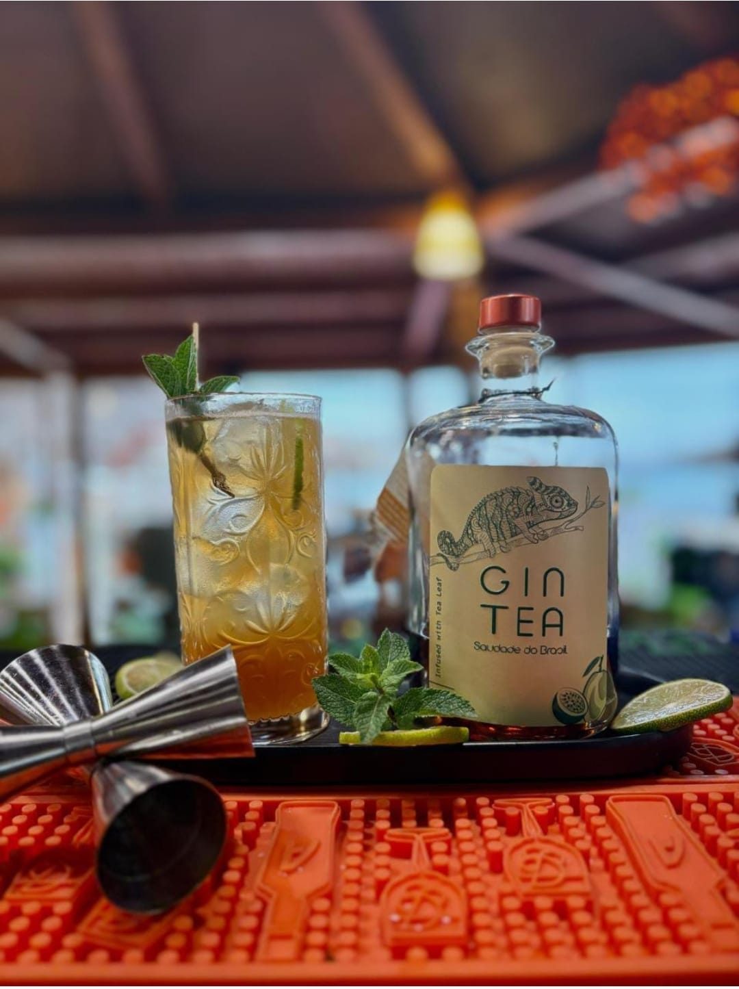Bottiglia Gin Tea Saudade do Brasil accanto a un cocktail Tonic in un bar